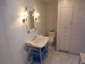 Elegant bathroom with white sink, blue shelves, and wall sconces.