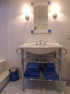 Clean bathroom sink with blue towels on the shelf below.